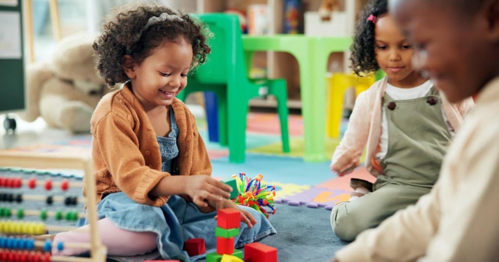Smiling toddlers playing with building blocks and toys on the floor